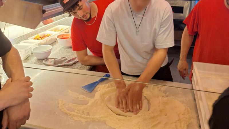 Un joven prepara la masa de la pizza